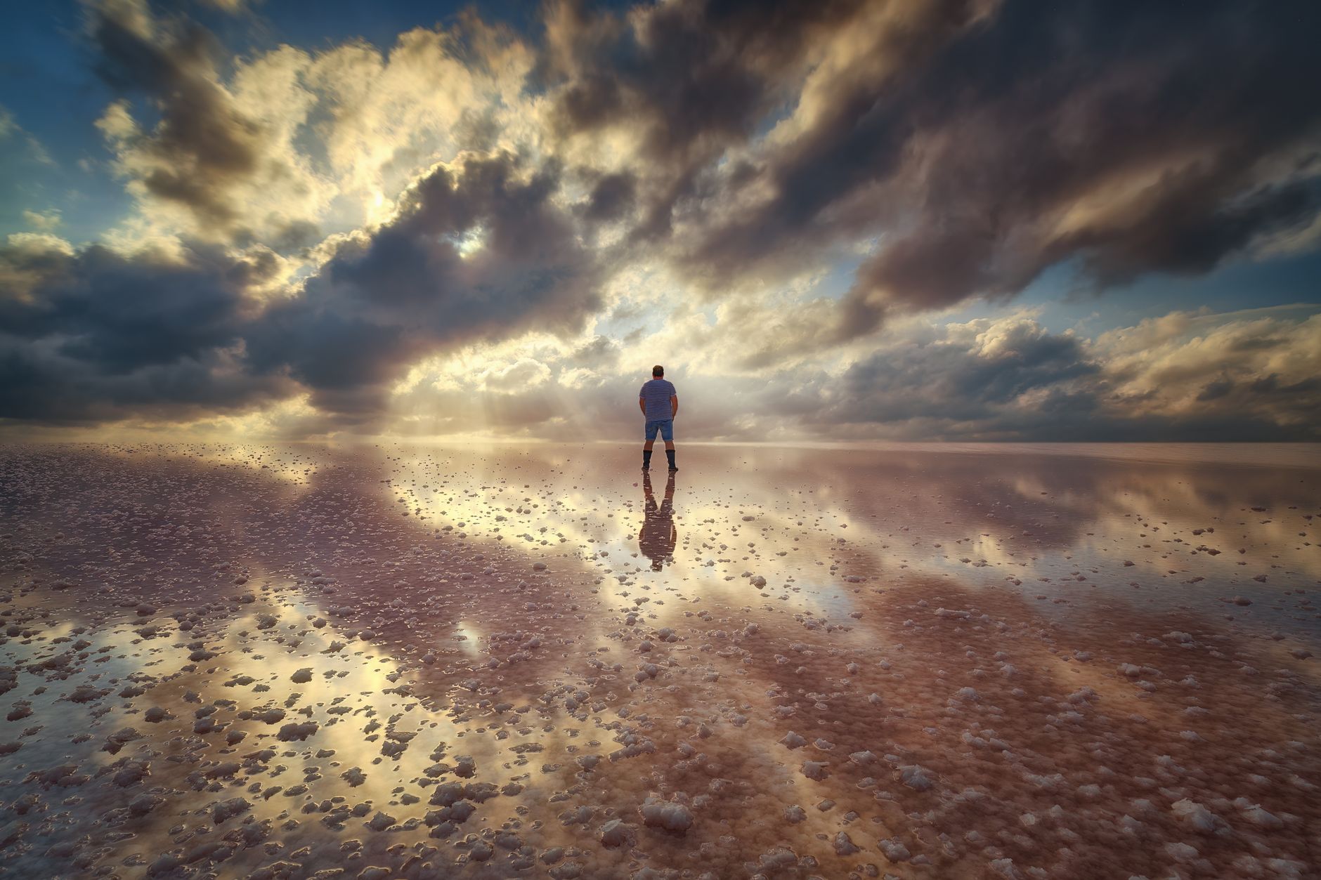 man standing on water on seashore at sunset